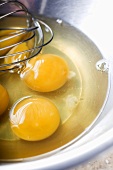 Cracked Cage-Free Eggs in a Bowl with Whisk