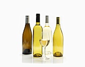 Glas Weißwein vor verschiedenen Weissweinflaschen