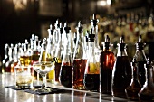 Many Bottles of Alcohol on Bar; Two Cocktails