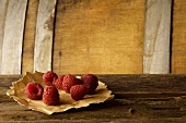 Himbeeren mit Papier auf Holzuntergrund