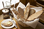 Verschiedene Brotscheiben im Brotkorb, Butterbrot und Marmeladengläser