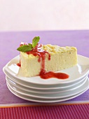 Slice of Cheesecake on Stacked Plates with Berry Sauce and Mint