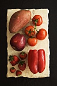 Rote Früchte und Gemüse auf einer Steinplatte