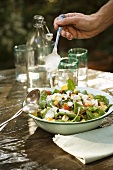 Spooning Creamy Dressing Over Spinach Salad with Bacon and Tomato
