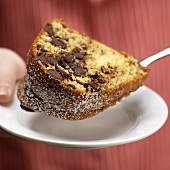 Person Holding a Slice of Chocolate Chip Bundt Cake on Spatula