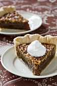 Two pieces of pecan pie with cream