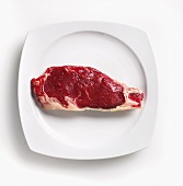 A raw steak on white plate