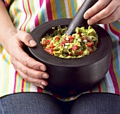 Woman Making Guacamole on Lap with Mortar and Pestle