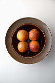 Four Blood Oranges in a Brown Bowl; From Above