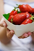 Frau hält Pappschale mit Erdbeeren