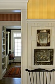 Englisch inspirierter Innenraum mit Harfenstühlen und alten Gemälden an halb getäfelter Wand mit Streifentapete