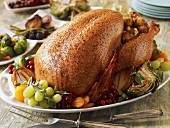Whole Roast Turkey on a Platter with Fruit; Side Dishes on Table