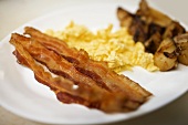 Breakfast of Bacon, Scrambled Eggs and Potatoes; On White Plate