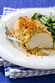 Baked Chicken Breast Coated in Mustard and Bread Crumbs; On Plate with Beans