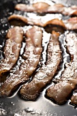 Thick Slices of Hickory Smoked Bacon Frying on Griddle
