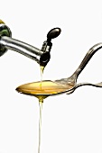 Olive Oil Being Poured and Spilling Over a Spoon