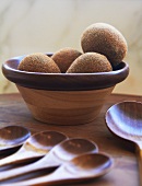 Kiwis in a Wooden Bowl; Many Wooden Spoons