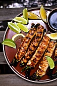 Grilled Chicken Negimaki (Thinly Pounded Chicken Breast Wrapped Around Scallions) on a Plate with Limes
