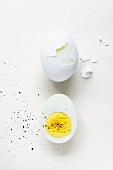 Half of a Hard Boiled Egg with Pepper; Partially Peeled Hard Boiled Egg