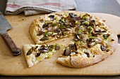 Flatbread Pizza Topped with Mushrooms and Onions; Sliced on Cutting Board