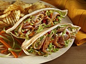 Shaved Pork Pita Sandwich with Chips and Carrot and Celery Garnish