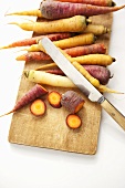Heirloom Carrots on a Cutting Board with Knife; One Chopped