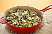 Pork and Rice Casserole with Peas and Mushrooms in a Red Pan
