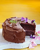 Chocolate Cake with Purple Flowers and Pink Paper Hearts; Slice Removed
