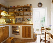 Gemauerte Küchenzeile im ländlichen Stil mit Holztüren, einem Küchenregal ums Eck und Bodenfliesen