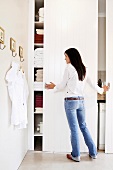 A woman standing in front of a sliding door in a large, white bathroom