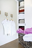 White blouses on hangers in the corner of a bathroom