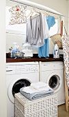 Kleidungsstücke und Wäsche in einem Kellerraum mit Waschmaschinen