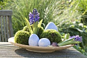 An Easter nest on a garden table with flowers and moss