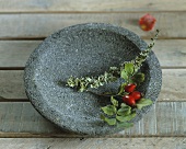 A sprig of rosehips in a stone bowl