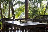 Terrasseneckplatz mit Korbmöbel auf der Veranda in tropischer Umgebung