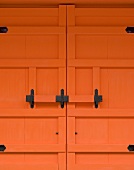 Ausschnitt eines orange lackierten Eingangstors mit schmiedeeisernem Schlossriegel