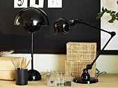 Black table lamps and writing implements on a light colored shelf