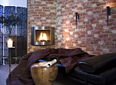 Comfy place to lie down with dark red throw covers in front of a wood burning stove and brick wall