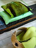 Green pillows with a pelt cover on wooden planks and basket with a coverlet