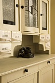 White crockery cupboard with porcelain storage containers and old fashioned telephone