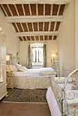 Antique white bed with cover under a timber frame roof in a bedroom of a country home