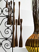 Collection of wooden sculptures next to decorative wrought iron with a floral design and willow basket with colorful fabric strips