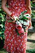 A woman holding a bunch of protea flowers behind her back