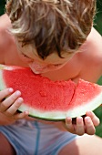 A little boy eating a slice of watermelon