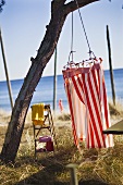 Baum mit rot-weiss gestreifter Umkleide am Strand mit Meerblick