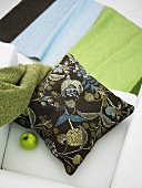 A patterned cushion and a green apple on a white armchair
