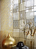 A golden vase and a patterned, transparent curtain