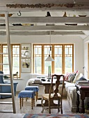 A living room with wooden beams in a country house with a dining area in front of a window