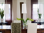 Decorative flowers on a wooden table with white lampshades handing above it