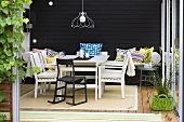 Cozy winter garden with white patio furniture in front of a black wall